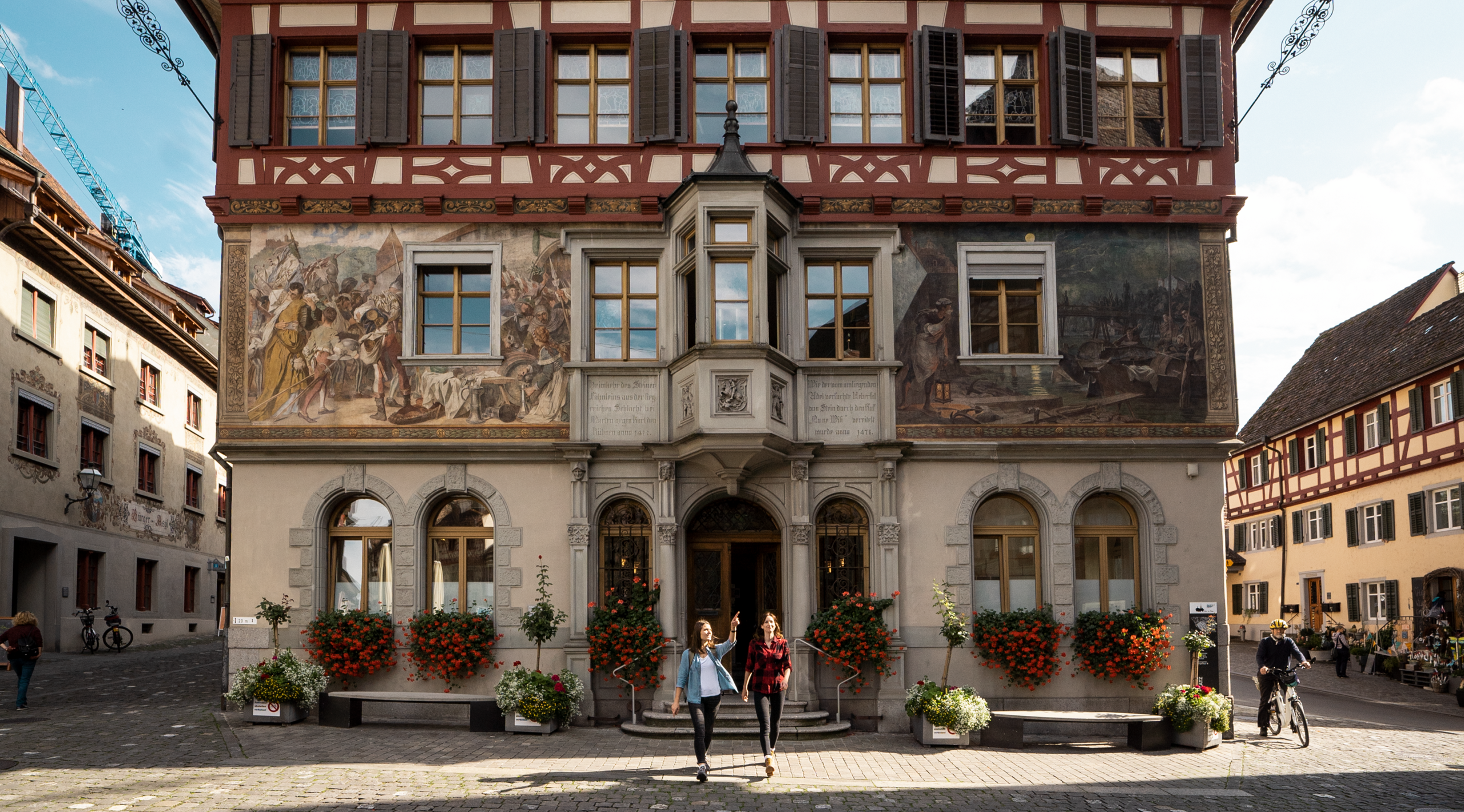 Zwei Wanderinnen stehen vor dem Rathaus in Stein am Rhein und starten ihre Wanderung.